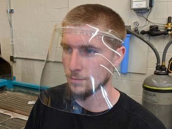 Logan Forquer, student worker, wears the face shield created by the Innovation Hub.